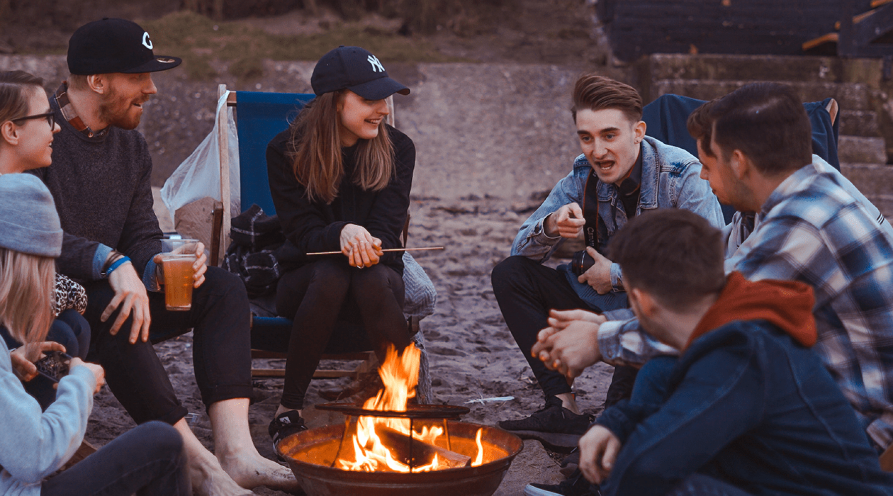 lifestyle image of a group of people relaxing outdoors around a campfire lifestyle image of a group of people relaxing outdoors around a campfire