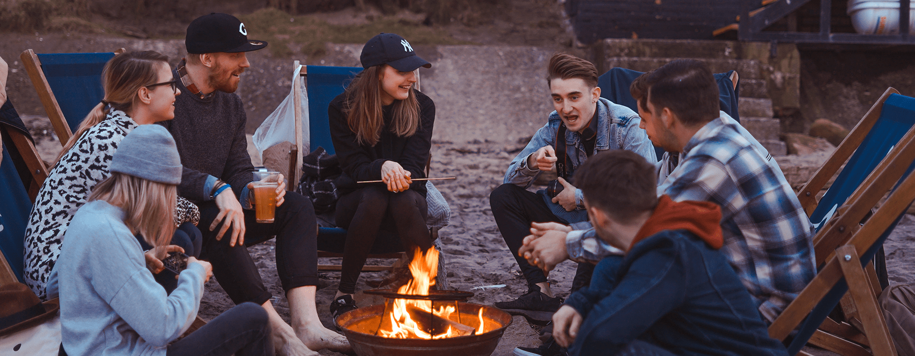lifestyle image of a group of people relaxing outdoors around a campfire